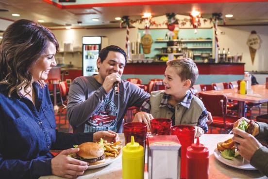 Dad, mom and son being served classic American burgers, fries and milkshakes by a singing server in Branson.