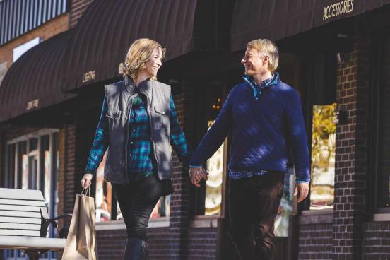 Man and women holding hands and walking through Downtown Branson. 