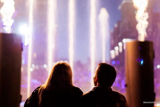 Couple standing in front of Branson Landing fire and fountain show in Branson.