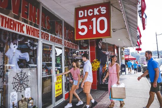 Family of four wearing cute summer clothes and walking into a historic nickle and dime store in downtown Branson. 