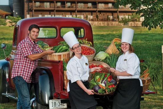 Three college students in the back of an old truck displaying fresh vegetables for a farmer's market in Branson.