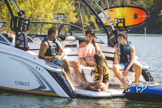 Family of four wearing swimsuits and sitting on the back of a speedboat on a lake in Branson.