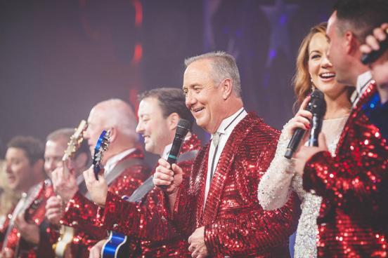 Line of live show music performers in red, white and blue costumes on a Branson stage.