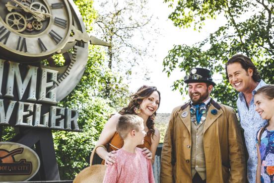 Family of four standing in front of Time Traveler roller coaster with Silver Dollar City staff member.