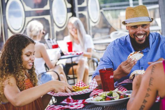 Family of three eating food on an outdoor patio by the lake in Branson. 