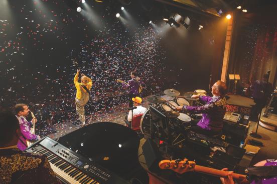 Live show performers singing and playing instruments on a stage surrounded by falling confetti in Branson.