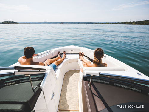Man and women sitting on the front of a speed boat on a lake in Branson.