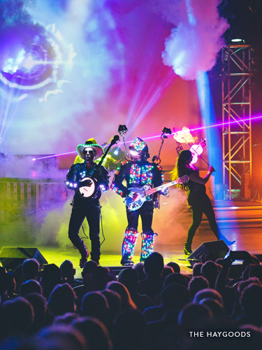 Three performers with lighted costumes and instruments on a live show stage in Branson.