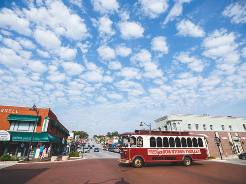 Free Downtown trolley driving in front of main street in Downtown Branson.