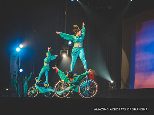 Four Chinese acrobats riding trick bikes on stage during a Branson live show.