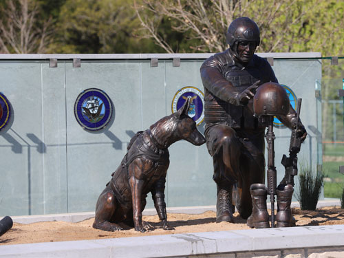 Statue of soldier kneeling and service dog in front of the Global War on Terrorism Memorial